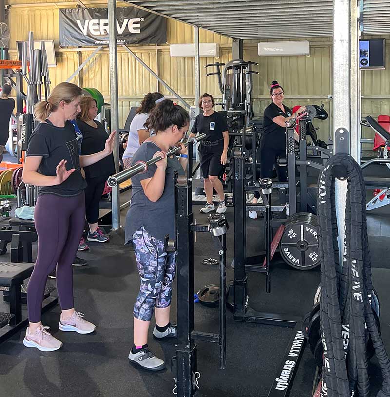 a group of woman in the gym lifting weights and getting in shape